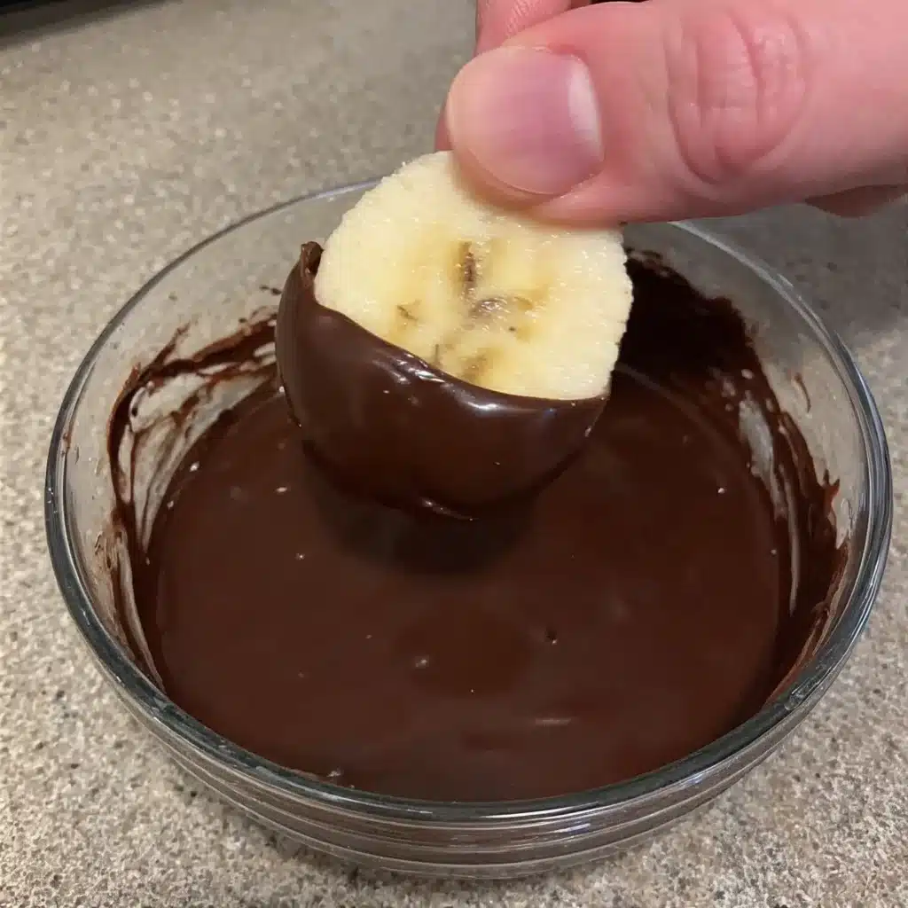 Frozen Banana Bites (Dairy-Free & Nut-Free Snack Idea) 4 Dipping banana slices into melted dairy-free chocolate